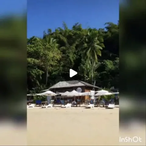A barraca vista da areia, com os guarda-sóis brancos