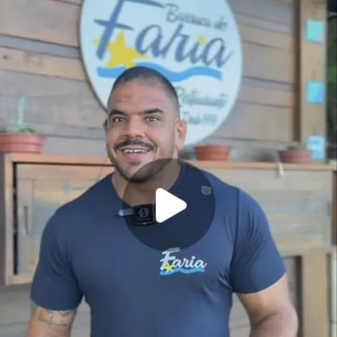 Victor Faria em frente à placa da barraca